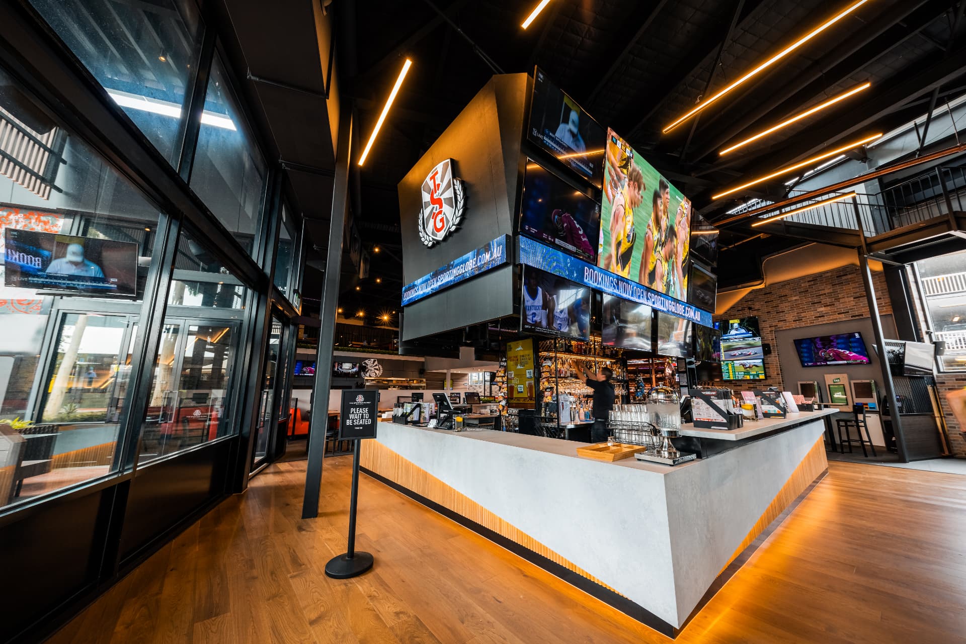 The Sporting Globe bar interior with illuminated signage and sports screens